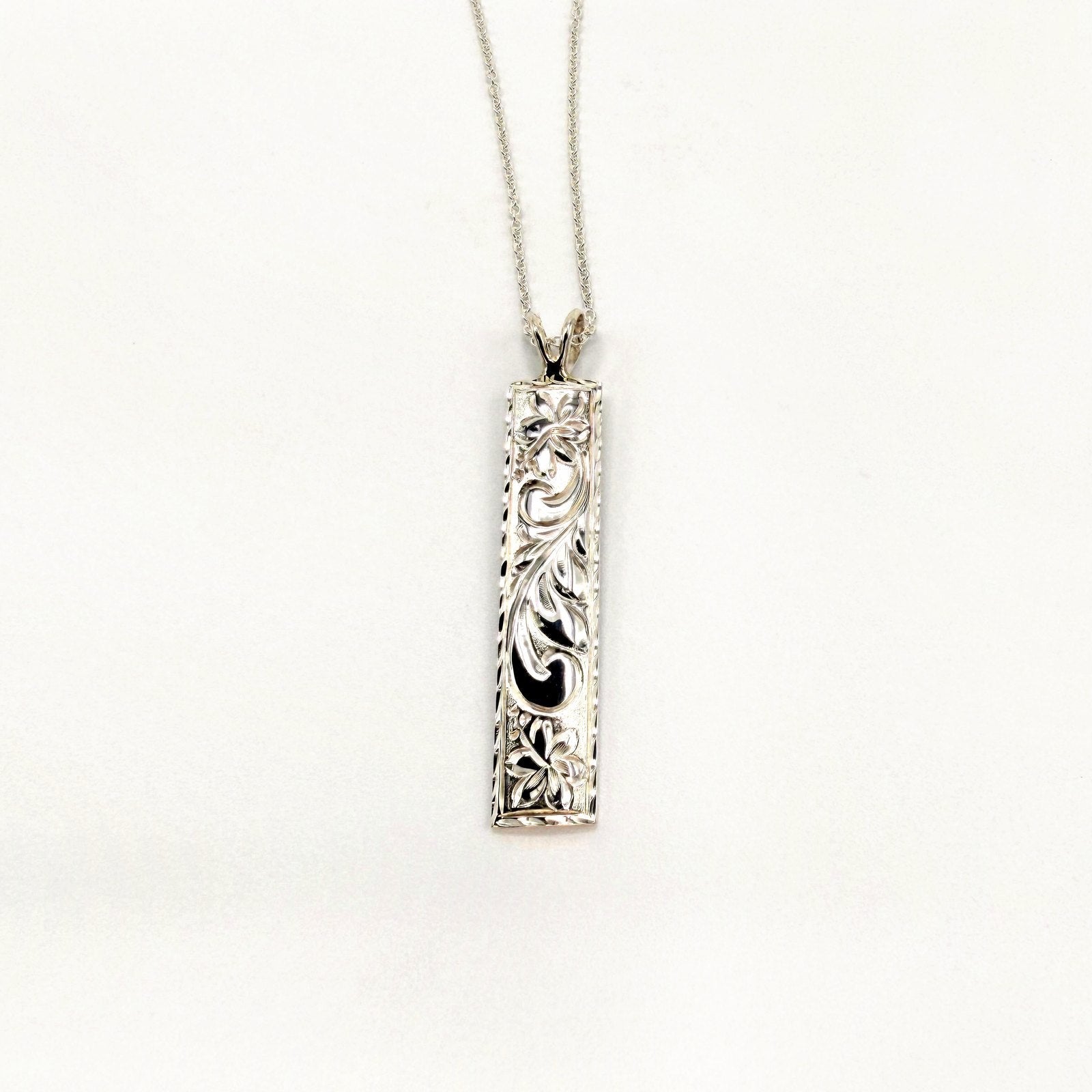 Silver bar pendant engraved with Hawaiian scroll and floral motifs on a fine chain