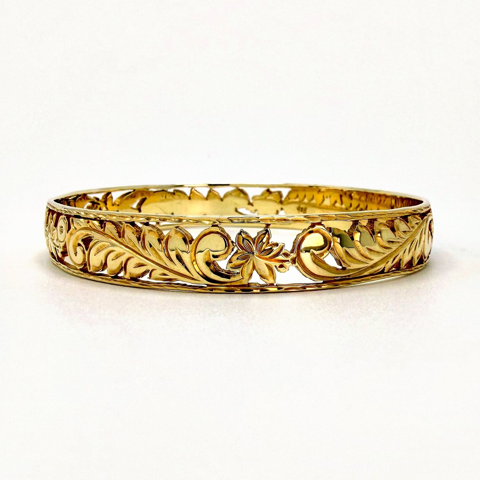 Gold open work filigree Hawaiian heirloom bangle bracelet with leaf and flower scroll cutouts, the kind of engraved detail that needs regular cleaning in Hawaii's salt air, handcrafted by Jewel Box Hawaii in Honolulu.
