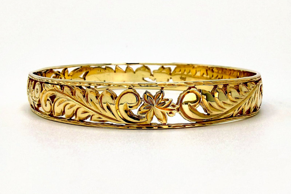 Gold open work filigree Hawaiian heirloom bangle bracelet with leaf and flower scroll cutouts, the kind of engraved detail that needs regular cleaning in Hawaii's salt air, handcrafted by Jewel Box Hawaii in Honolulu.