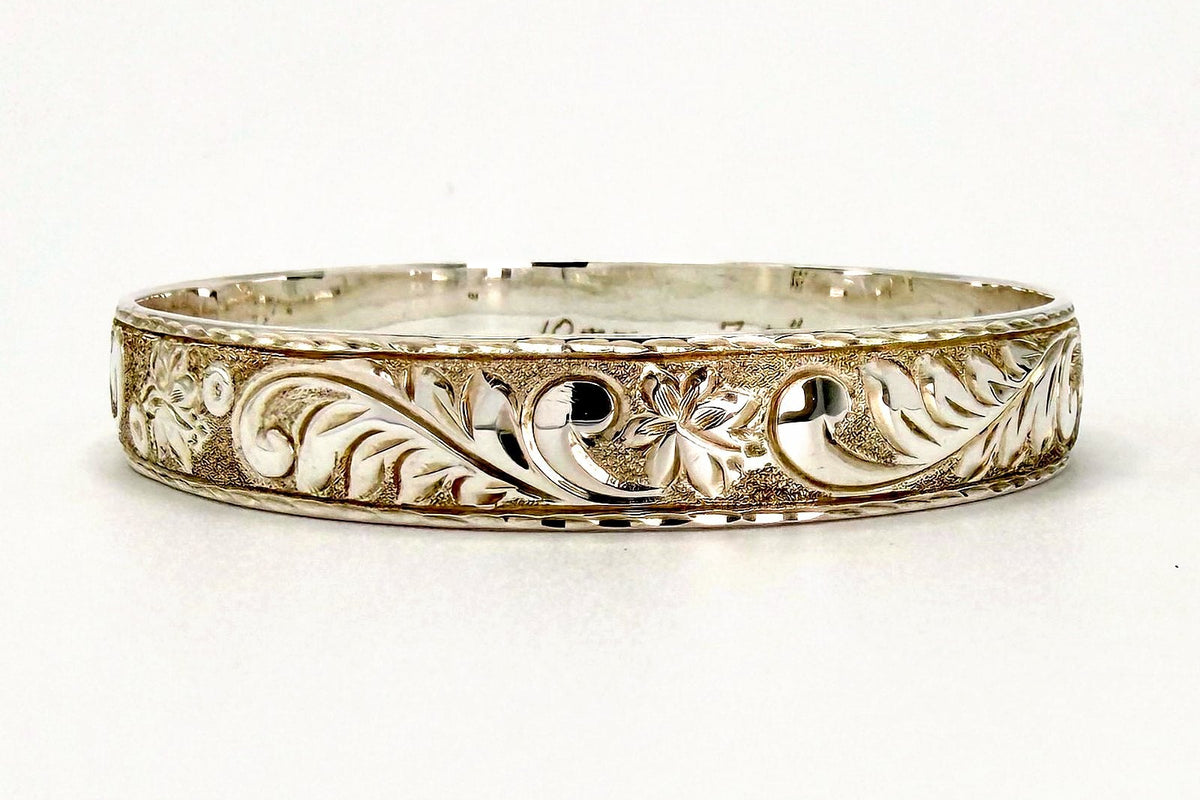 Sterling silver 10mm Hawaiian heirloom bangle bracelet with high relief plumeria and leaf scroll hand engraving, handcrafted by Jewel Box Hawaii in Honolulu.