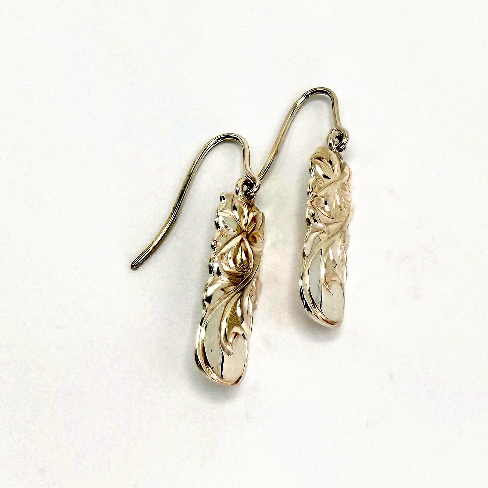 Pair of Hawaiian scroll elongated gold drop earrings with hand engraved floral scroll motif and wire hooks, handcrafted by Jewel Box Hawaii in Honolulu.