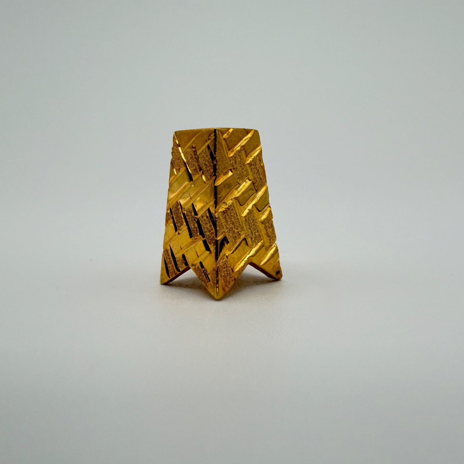 A tapered gold slide pendant with a diamond cut woven texture, on a light grey background.