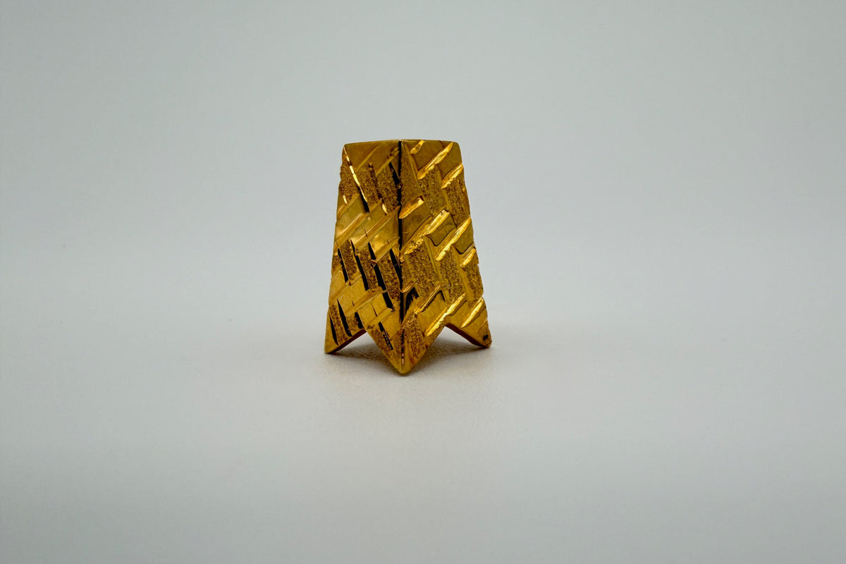 A tapered gold slide pendant with a diamond cut woven texture, on a light grey background.
