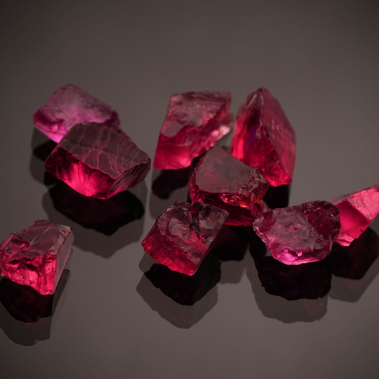 Vibrant red ruby gemstones on a dark reflective surface, July's birthstone