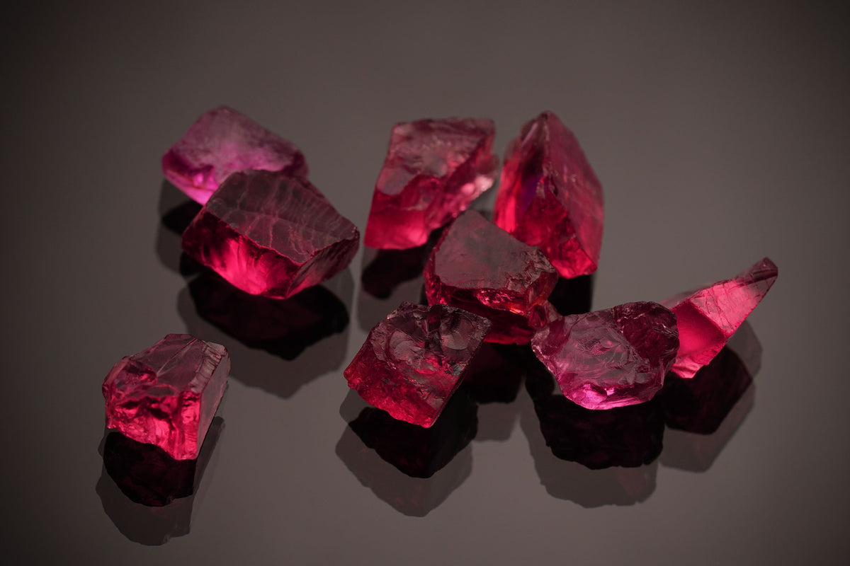 Vibrant red ruby gemstones on a dark reflective surface, July's birthstone