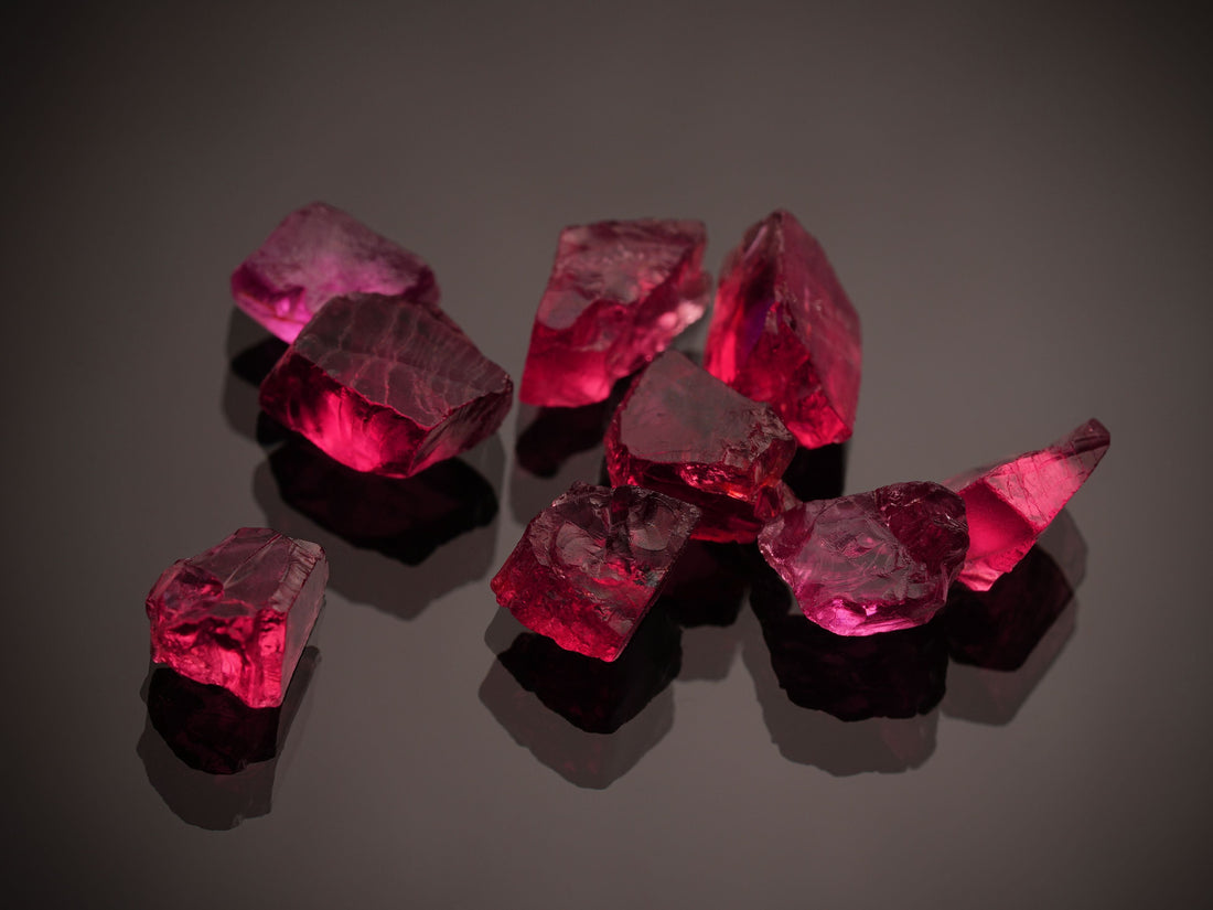 Vibrant red ruby gemstones on a dark reflective surface — July's birthstone