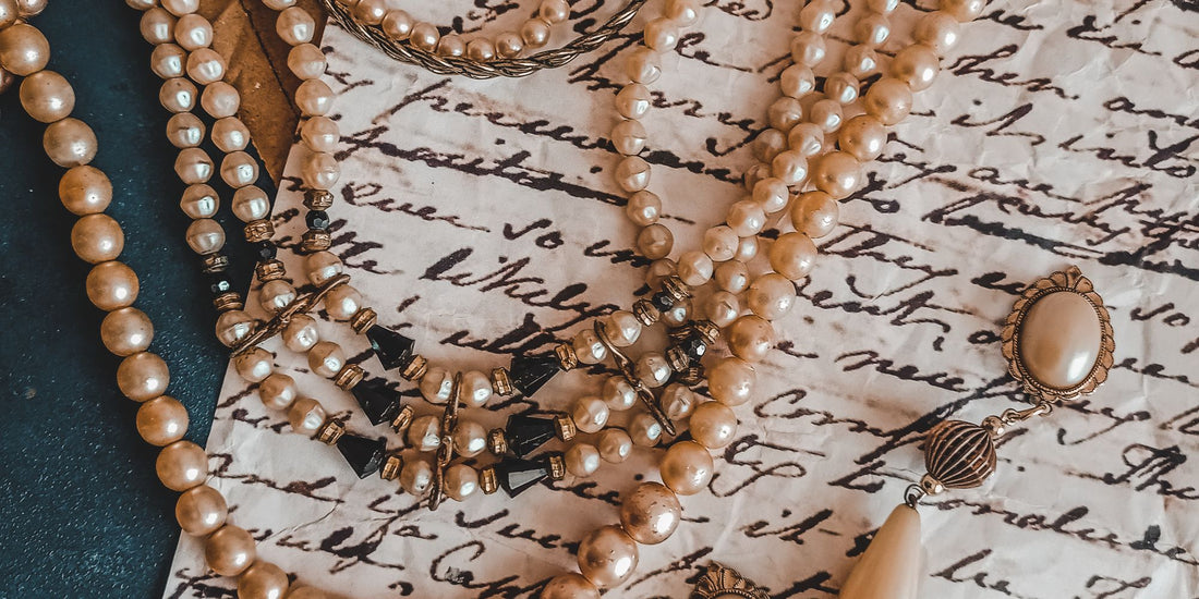 Antique pearl necklace and earrings resting on a vintage handwritten letter, representing inherited heirloom jewelry