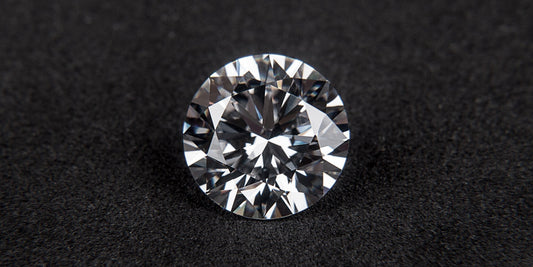 Round brilliant cut diamond on a dark textured surface — April's birthstone