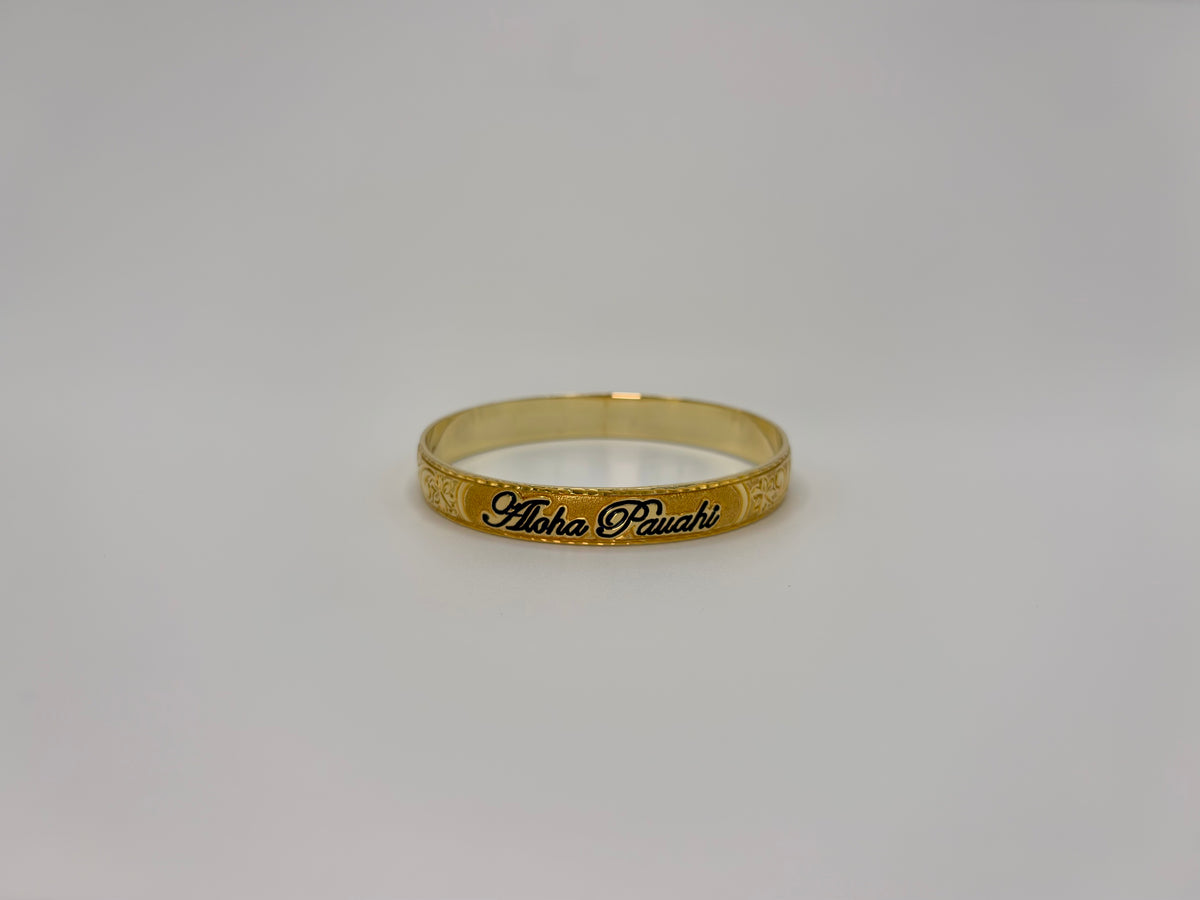 Aloha Pauahi gold Hawaiian heirloom bangle bracelet with a black enamel nameplate and hand engraved plumeria and maile leaf scrollwork, handcrafted by Jewel Box Hawaii in Honolulu.