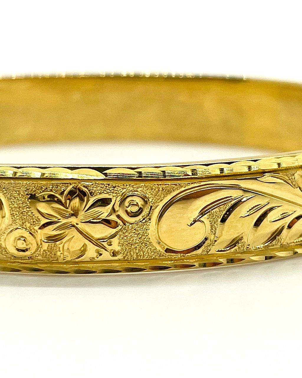Hand engraved blossom and scroll pattern on a gold Aloha Pauahi heirloom bangle.
